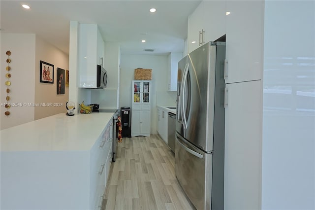 kitchen with white cabinetry, appliances with stainless steel finishes, and light wood-type flooring