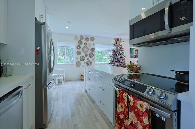 kitchen with light hardwood / wood-style flooring, white cabinets, and stainless steel appliances