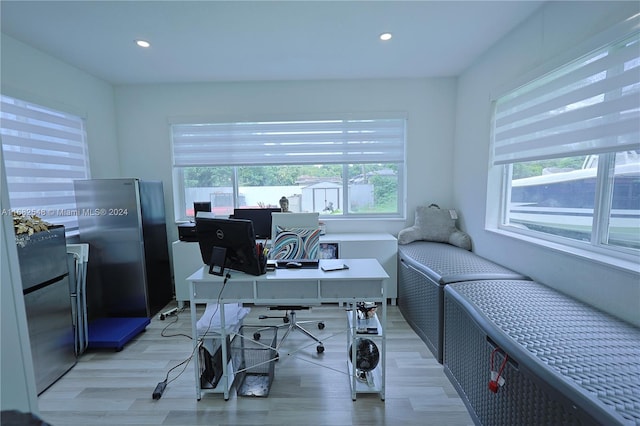 office area with light hardwood / wood-style floors and a healthy amount of sunlight