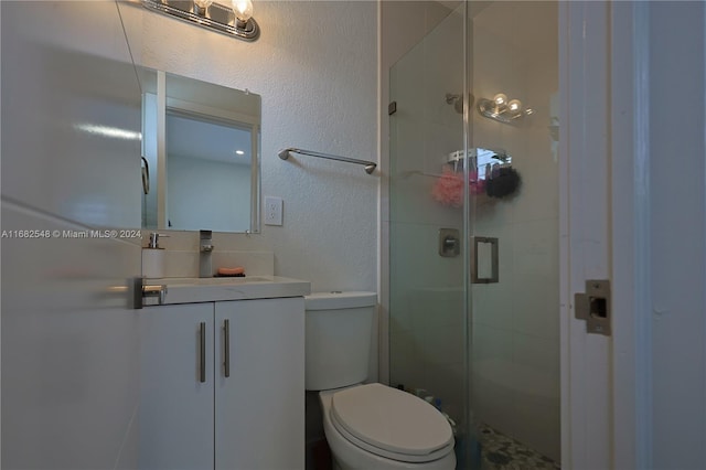 bathroom with toilet, a shower with shower door, and vanity