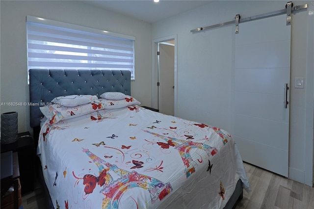 bedroom with light hardwood / wood-style flooring and a barn door