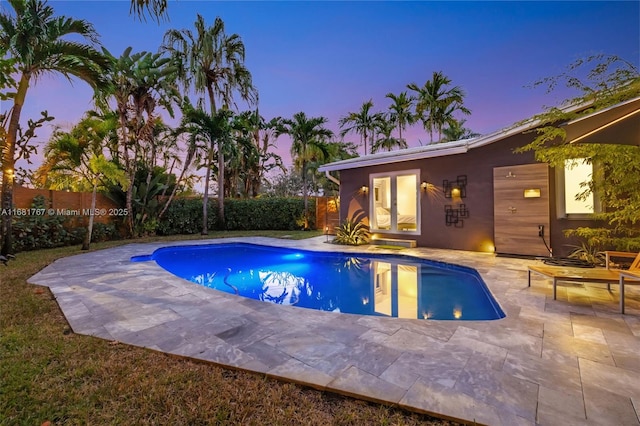 pool at dusk with a fenced in pool, a fenced backyard, and a patio