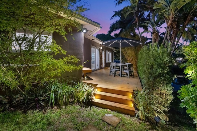 deck at dusk featuring outdoor dining area