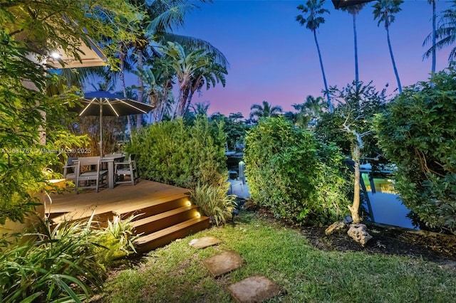 yard at dusk with a deck with water view