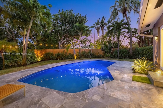 pool at dusk featuring a fenced backyard, a fenced in pool, and a patio