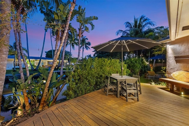 wooden terrace with outdoor dining area and a water view