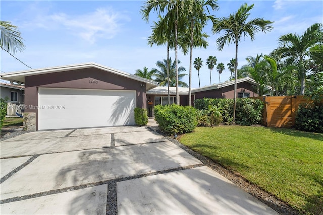 single story home with concrete driveway, stucco siding, an attached garage, fence, and a front yard