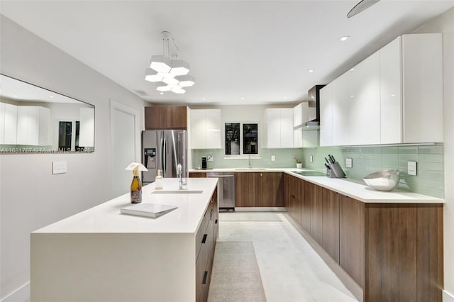 kitchen featuring light countertops, appliances with stainless steel finishes, white cabinets, wall chimney range hood, and modern cabinets