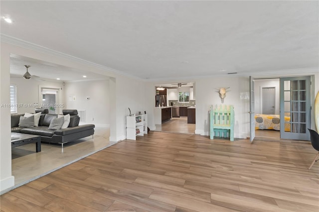 living area with light wood-style flooring, baseboards, ceiling fan, and crown molding