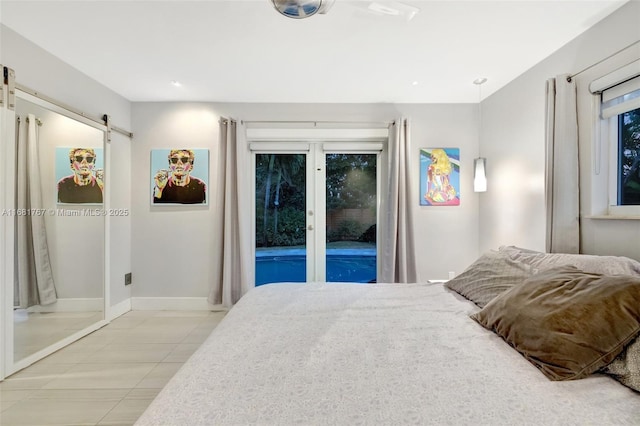 bedroom with access to exterior, a barn door, light tile patterned floors, and baseboards