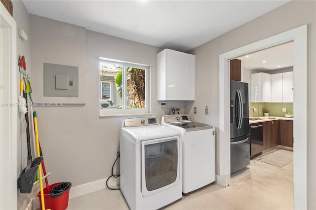 clothes washing area featuring a sink, baseboards, independent washer and dryer, cabinet space, and electric panel