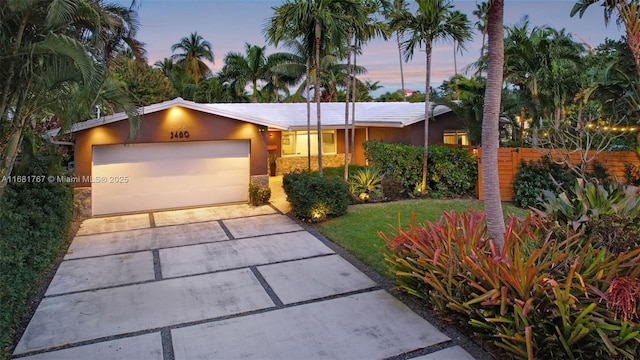 view of front of house with a garage, driveway, fence, and stucco siding