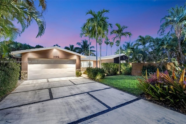 view of front of property featuring an attached garage, a front yard, concrete driveway, and stucco siding