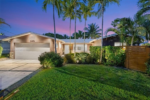 view of front of property featuring a garage, driveway, a lawn, and stucco siding