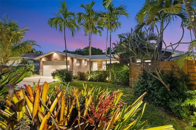 view of front of property featuring a front yard, driveway, an attached garage, and stucco siding