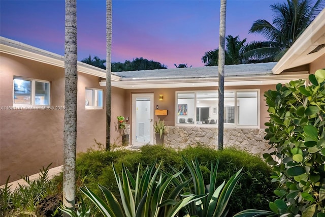 entrance to property featuring stone siding and stucco siding