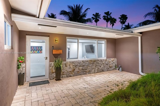 view of exterior entry with stone siding and stucco siding