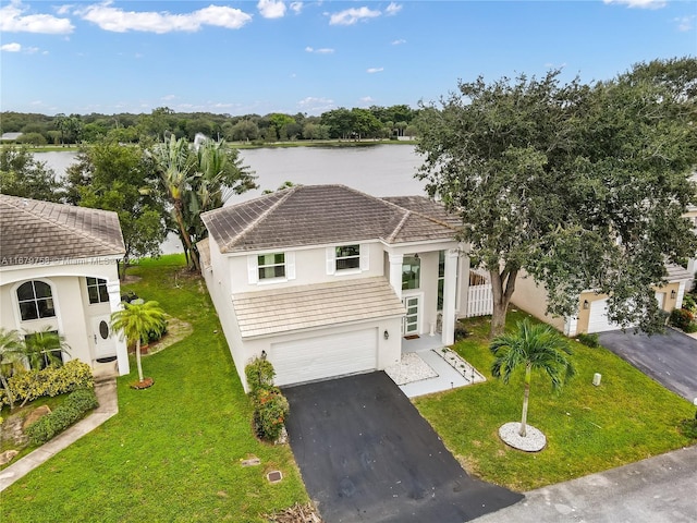 view of front of home with a garage, a water view, and a front lawn