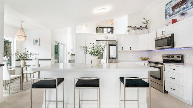 kitchen featuring white cabinets, a center island, stainless steel appliances, and hanging light fixtures