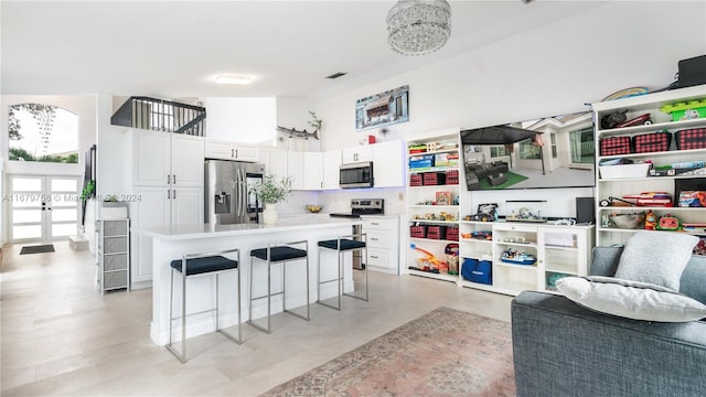 kitchen with a center island, a high ceiling, a kitchen breakfast bar, appliances with stainless steel finishes, and white cabinetry