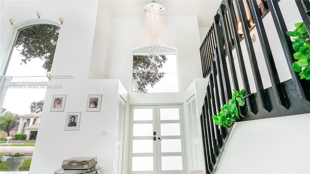 foyer entrance with french doors, a towering ceiling, and an inviting chandelier