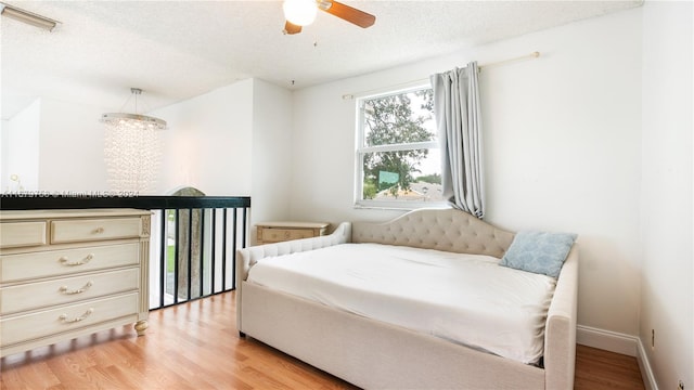 bedroom featuring a textured ceiling, light wood-type flooring, and ceiling fan