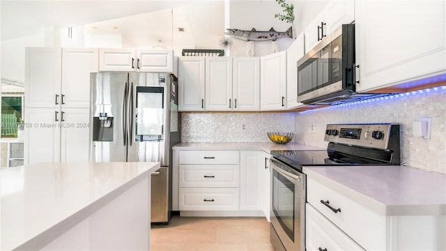 kitchen featuring white cabinetry, backsplash, lofted ceiling, light tile patterned flooring, and appliances with stainless steel finishes