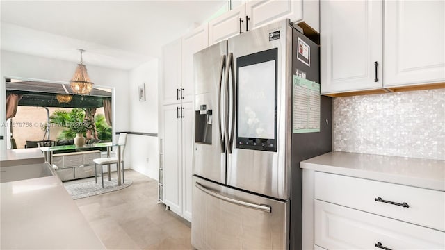 kitchen with stainless steel refrigerator with ice dispenser, tasteful backsplash, sink, pendant lighting, and white cabinets