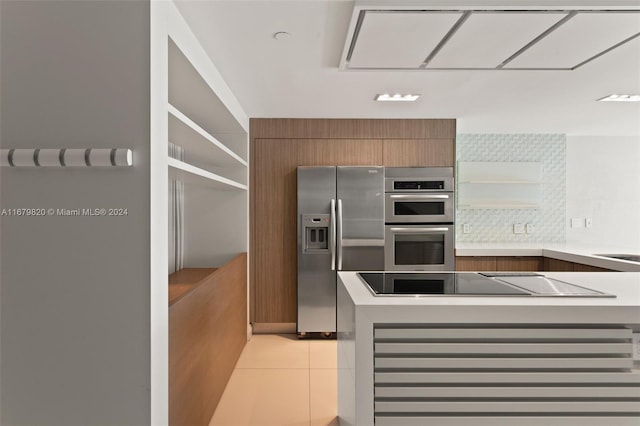 kitchen featuring light tile patterned flooring, stainless steel appliances, and tasteful backsplash