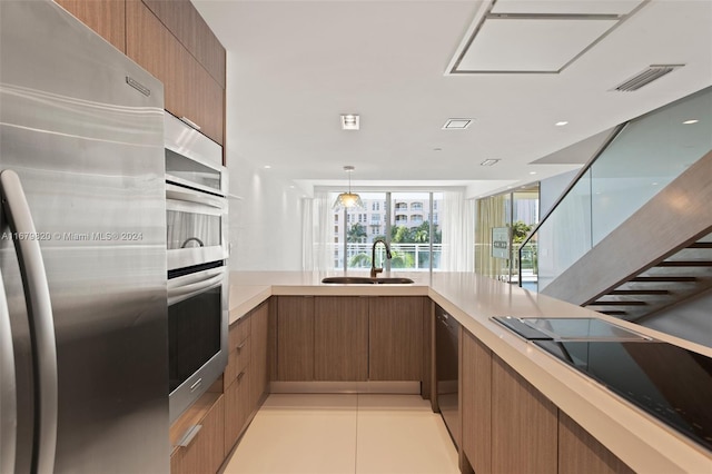 kitchen with light tile patterned floors, appliances with stainless steel finishes, sink, and pendant lighting