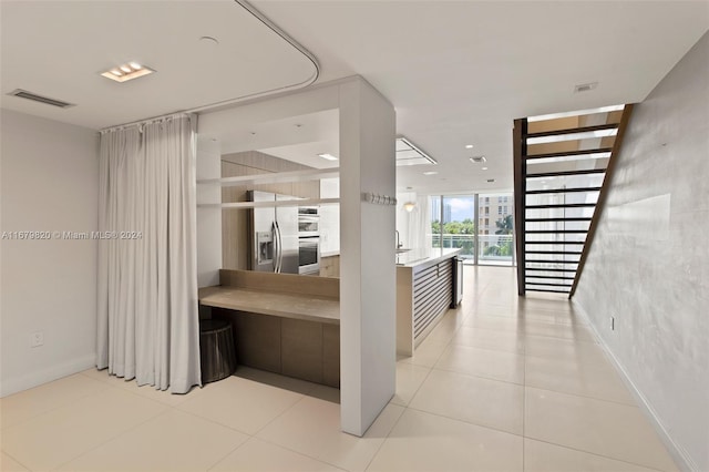 corridor with sink, expansive windows, and light tile patterned flooring