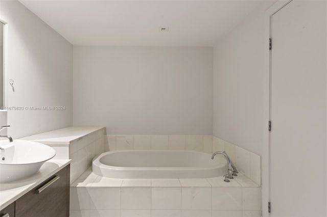 bathroom with vanity and tiled tub