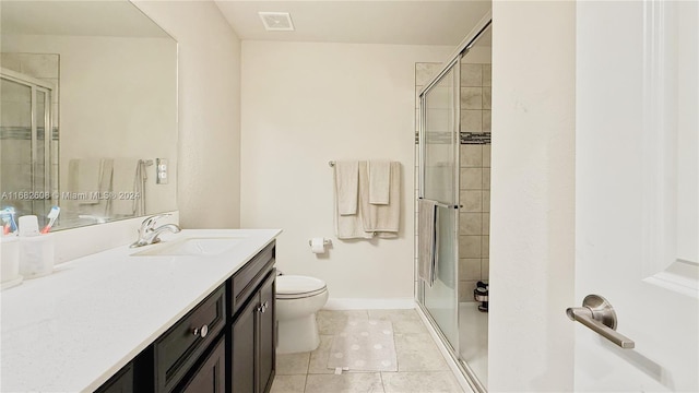 bathroom featuring toilet, vanity, tile patterned floors, and a shower with shower door