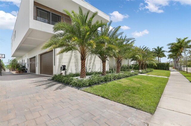 view of side of property featuring a garage and a lawn