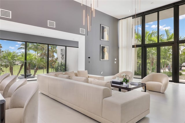 living area with light tile patterned floors, plenty of natural light, visible vents, and a wall of windows