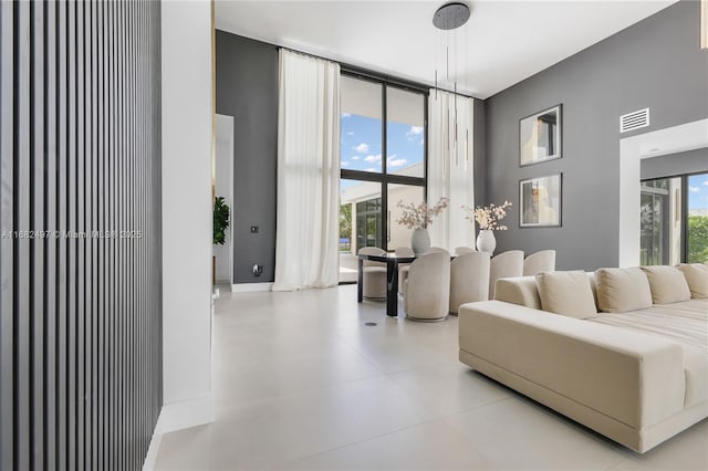 living room with floor to ceiling windows, visible vents, and baseboards