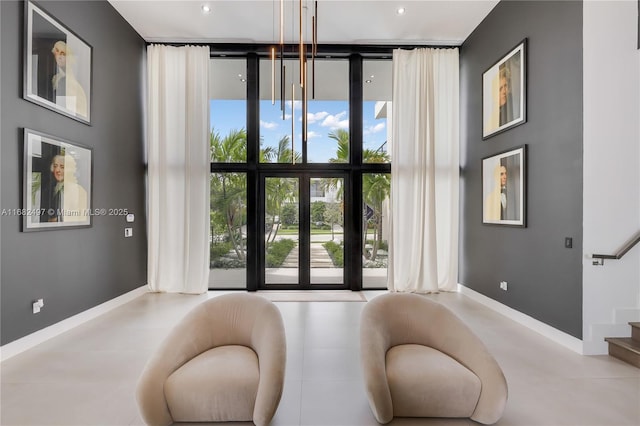 entryway featuring baseboards, a high ceiling, stairway, and floor to ceiling windows