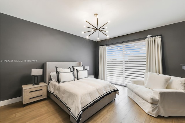 bedroom featuring baseboards, an inviting chandelier, and wood finished floors