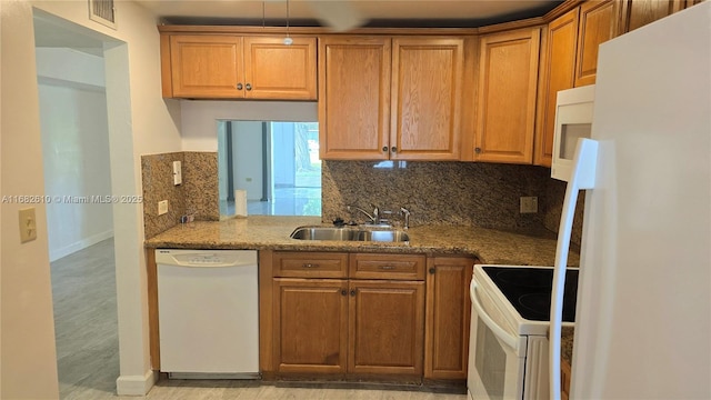 kitchen featuring tasteful backsplash, sink, stone countertops, and white appliances