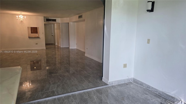 unfurnished room featuring an inviting chandelier