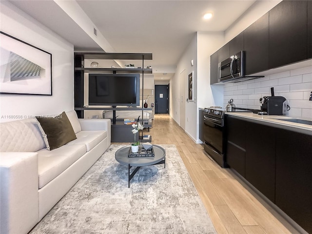 living room featuring sink, a wood stove, and light hardwood / wood-style flooring