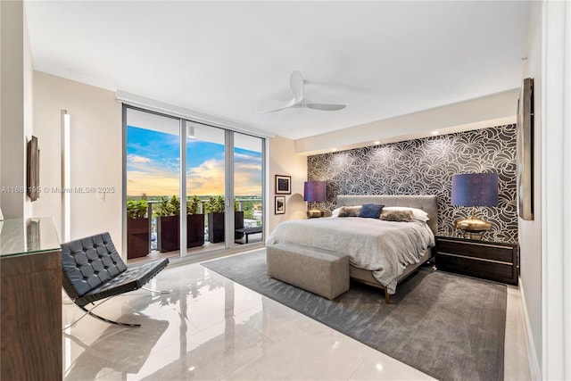 bedroom featuring wallpapered walls, an accent wall, marble finish floor, access to outside, and a wall of windows