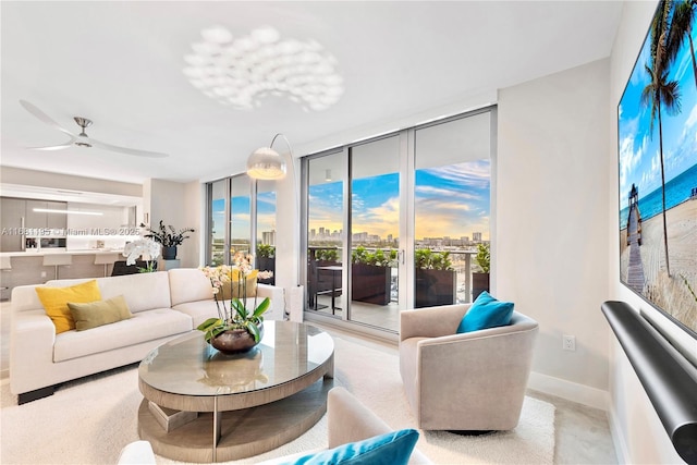 living room with a view of city, floor to ceiling windows, ceiling fan, and baseboards