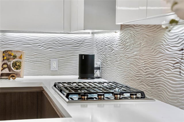 interior details with stainless steel gas stovetop, light countertops, and backsplash