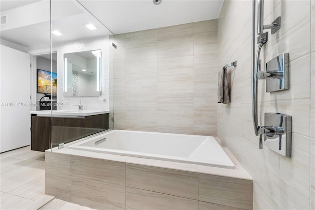 full bathroom featuring tile walls, visible vents, a tile shower, vanity, and tiled tub