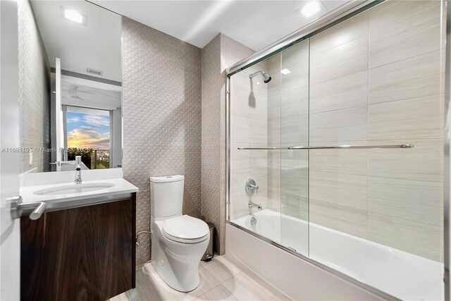 bathroom with tile patterned floors, vanity, toilet, and bath / shower combo with glass door