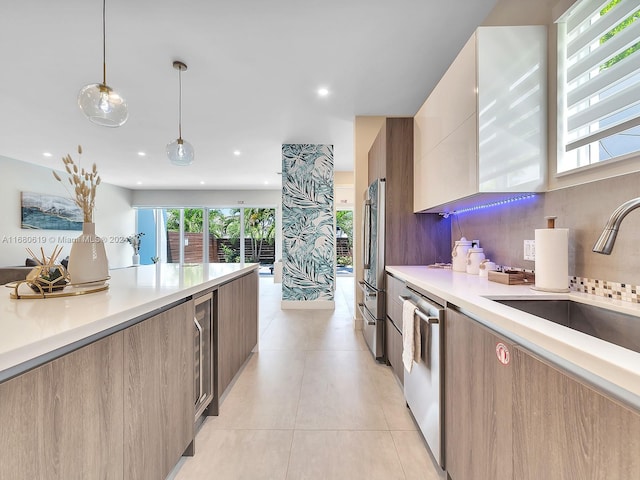 kitchen with appliances with stainless steel finishes, light tile patterned flooring, sink, backsplash, and hanging light fixtures