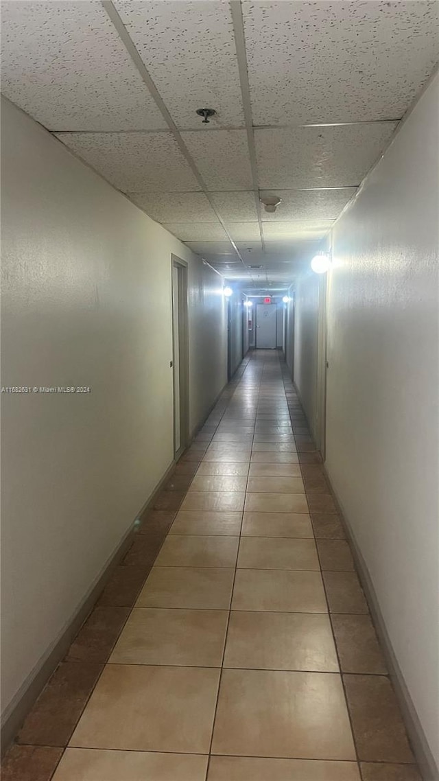 corridor featuring a paneled ceiling and tile patterned flooring