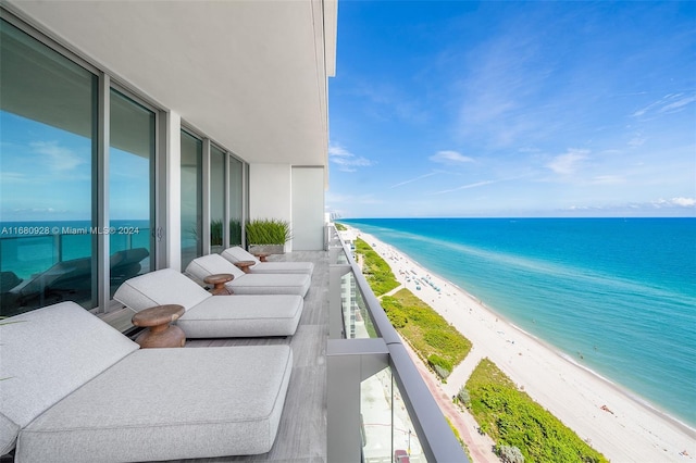 balcony featuring a view of the beach and a water view