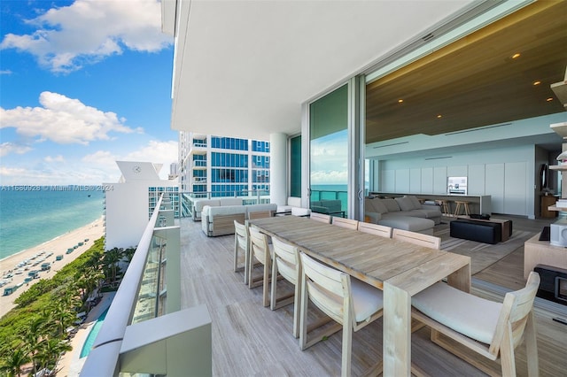 balcony with an outdoor hangout area, a water view, and a view of the beach